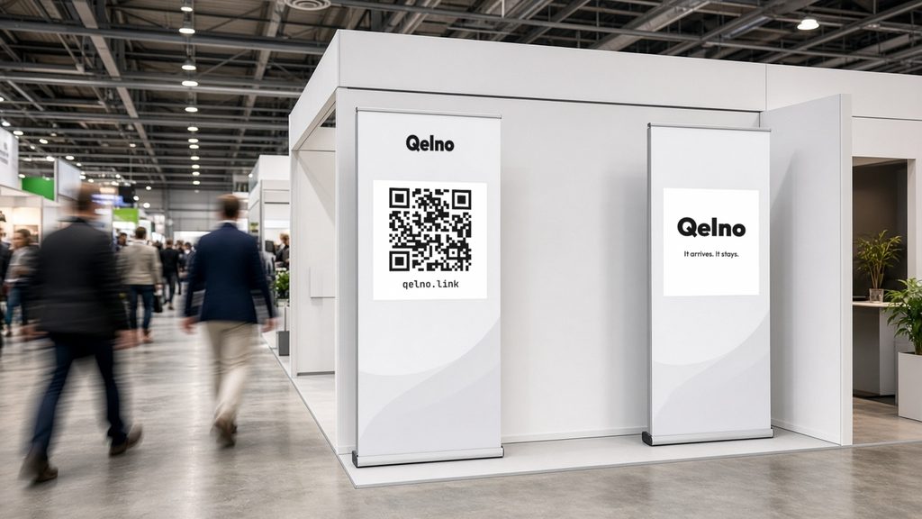 Messestand mit zwei Roll-ups: links das Zeichen Qelno, ein QR-Code und die Adresse qelno.link, rechts das Zeichen Qelno mit der Zeile It arrives. It stays. Im Gang gehen Besucher vorbei.